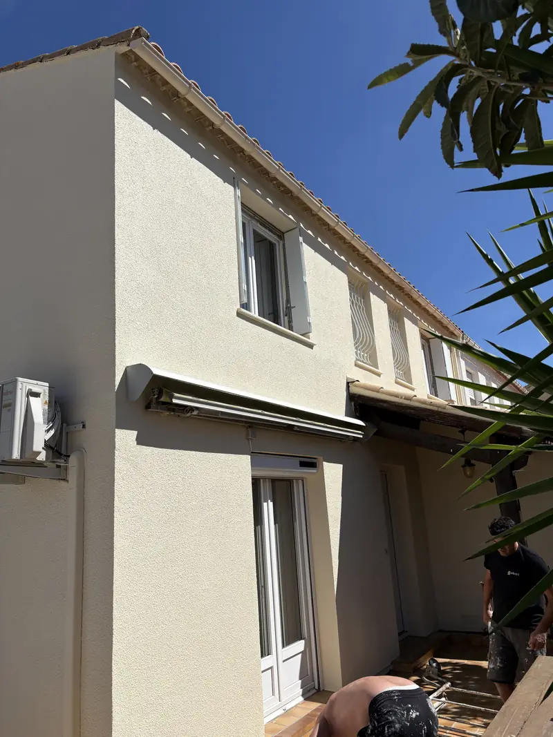 Peinture de façade extérieure à Béziers — mur crépi beige et volets blancs sur maison de ville