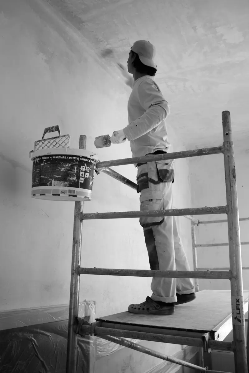 Artisan peintre appliquant un enduit au plafond sur échafaudage intérieur