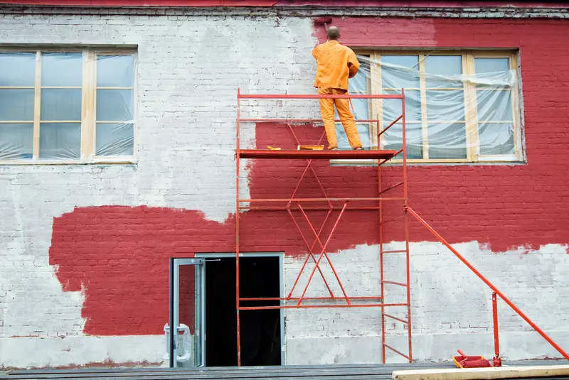 Ravalement de façade sur échafaudage — application de peinture extérieure sur bâtiment