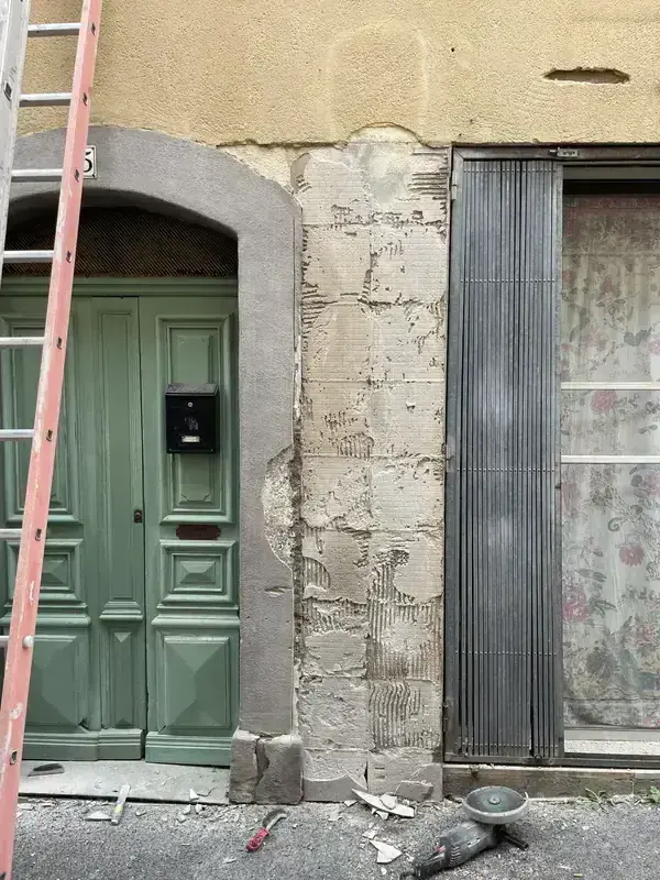 Façade avant ravalement à Béziers — enduit dégradé et porte de garage verte