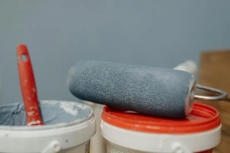 Rouleau et pots de peinture grise — matériel de peintre professionnel
