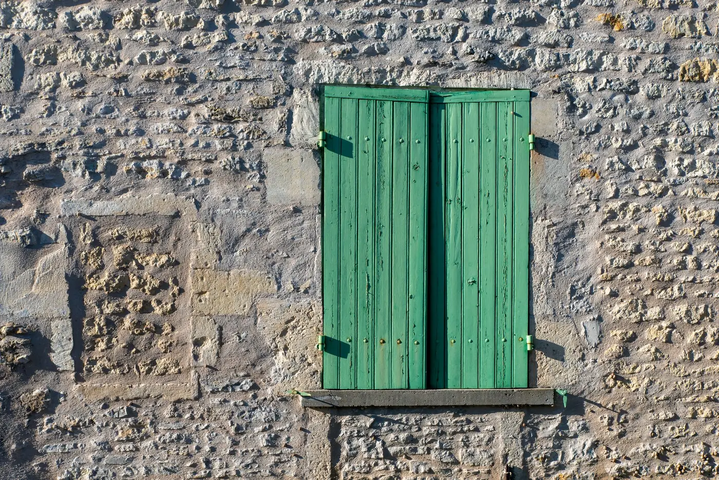 Mur en pierre ancien avec enduit à la chaux et volets, maison du Biterrois